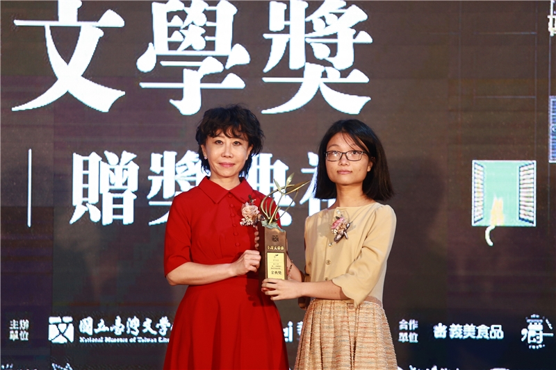 何玟珒《那一天我們跟在雞屁股後面尋路》榮獲金典獎，由國立臺灣文學館長林巾力（左）頒發獎座。