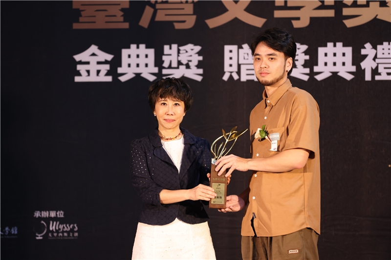 張貴興《鱷眼晨曦》榮獲金典獎，由公子張先羚（右）代為領獎，國立臺灣文學館長林巾力（左）頒發獎座。